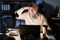 Middle age man with grey hair working at the office at night very happy and smiling looking far away with hand over head Royalty Free Stock Photo