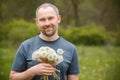 Middle age man holding a bunch of first white dandelions