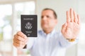 Middle age man holding holding passport of United States with open hand doing stop sign with serious and confident expression, Royalty Free Stock Photo