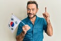 Middle age man holding south korea flag smiling with an idea or question pointing finger with happy face, number one Royalty Free Stock Photo