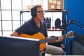 Middle age man musician singing song playing classical guitar at music studio Royalty Free Stock Photo