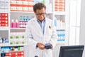 Middle age man pharmacist using credit card and data phone at pharmacy Royalty Free Stock Photo
