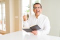 Middle age man reading a book at home wearing glasses screaming proud and celebrating victory and success very excited, cheering Royalty Free Stock Photo