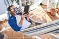 Middle age man reading book lying on hammock at terrace home Royalty Free Stock Photo