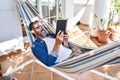 Middle age man reading book lying on hammock at terrace home Royalty Free Stock Photo