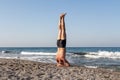 Middle age Man in shorts is doing his morning exercises on the beach by the sea. Headstand Royalty Free Stock Photo