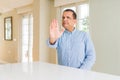 Middle age man sitting at home doing stop sing with palm of the hand Royalty Free Stock Photo