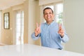 Middle age man sitting at home smiling looking to the camera showing fingers doing victory sign Royalty Free Stock Photo