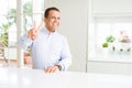 Middle age man sitting at home smiling looking to the camera showing fingers doing victory sign Royalty Free Stock Photo