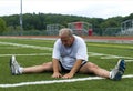 Middle age man stretching on sports field Royalty Free Stock Photo