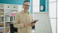 Middle age man teacher teaching lesson holding book at classroom Royalty Free Stock Photo