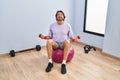 Middle age man training with dumbbells sitting on fit ball at sport center Royalty Free Stock Photo