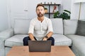 Middle age man using laptop at home making fish face with lips, crazy and comical gesture Royalty Free Stock Photo