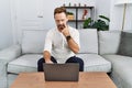 Middle age man using laptop at home pointing to the eye watching you gesture, suspicious expression Royalty Free Stock Photo