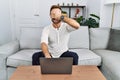 Middle age man using laptop at home smiling and laughing with hand on face covering eyes for surprise Royalty Free Stock Photo