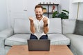 Middle age man using laptop at home very happy and excited doing winner gesture with arms raised, smiling and screaming for Royalty Free Stock Photo