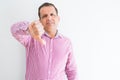 Middle age man wearing business shirt over white wall looking unhappy and angry showing rejection and negative with thumbs down Royalty Free Stock Photo