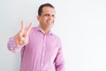 Middle age man wearing business shirt over white wall smiling looking to the camera showing fingers doing victory sign Royalty Free Stock Photo