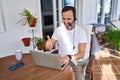 Middle age man wearing call center agent headset working from home smiling happy and positive, thumb up doing excellent and Royalty Free Stock Photo