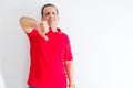 Middle age man wearing red t-shirt over white wall looking unhappy and angry showing rejection and negative with thumbs down Royalty Free Stock Photo