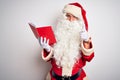 Middle age man wearing Santa Claus costume reading book over isolated white background pointing fingers to camera with happy and Royalty Free Stock Photo