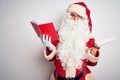 Middle age man wearing Santa Claus costume reading book over isolated white background smiling cheerful presenting and pointing Royalty Free Stock Photo