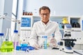 Middle age man wearing scientist uniform looking test tubes at laboratory Royalty Free Stock Photo