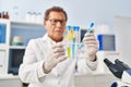 Middle age man wearing scientist uniform looking test tubes at laboratory Royalty Free Stock Photo