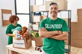 Middle age man wearing volunteer t shirt at donations stand happy face smiling with crossed arms looking at the camera Royalty Free Stock Photo
