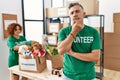 Middle age man wearing volunteer t shirt at donations stand looking confident at the camera with smile with crossed arms and hand Royalty Free Stock Photo