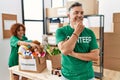 Middle age man wearing volunteer t shirt at donations stand looking confident at the camera smiling with crossed arms and hand Royalty Free Stock Photo