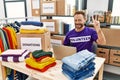 Middle age man wearing volunteer t shirt working with laptop showing and pointing up with fingers number three while smiling