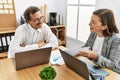 Middle age man and woman business workers using laptop and document working at office Royalty Free Stock Photo