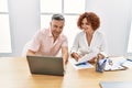 Middle age man and woman business workers using laptop and reading document at office Royalty Free Stock Photo