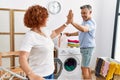 Middle age man and woman couple high five raised up hands hanging clothes at laundry Royalty Free Stock Photo