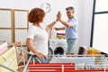 Middle age man and woman couple high five raised up hands hanging clothes at laundry Royalty Free Stock Photo