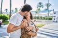 Middle age man and woman couple holding chihuahua hugging each other and kissing at street Royalty Free Stock Photo