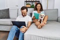 Middle age man and woman couple using laptop and reading book sitting on sofa with chihuahua at home Royalty Free Stock Photo