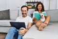 Middle age man and woman couple using laptop and reading book sitting on sofa with chihuahua at home Royalty Free Stock Photo