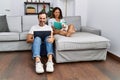 Middle age man and woman couple using laptop and reading book sitting on sofa with chihuahua at home Royalty Free Stock Photo