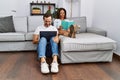 Middle age man and woman couple using laptop and reading book sitting on sofa with chihuahua at home Royalty Free Stock Photo