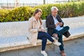 Middle age man and woman couple using smartphone sitting on bench at park Royalty Free Stock Photo