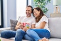 Middle age man and woman couple watching movie sitting on sofa at home Royalty Free Stock Photo