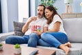 Middle age man and woman couple watching movie sitting on sofa at home Royalty Free Stock Photo