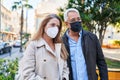 Middle age man and woman couple wearing medical mask standing at park Royalty Free Stock Photo