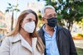 Middle age man and woman couple wearing medical mask standing at park Royalty Free Stock Photo