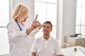 Middle age man and woman doctor and patient examining vision having medical consultation at clinic Royalty Free Stock Photo