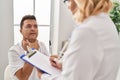 Middle age man and woman doctor and patient having medical consultation at clinic Royalty Free Stock Photo