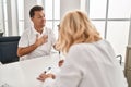 Middle age man and woman doctor and patient using inhaler having medical consultation at clinic Royalty Free Stock Photo