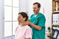 Middle age man and woman massaging neck having rehab session at physiotherapy clinic Royalty Free Stock Photo